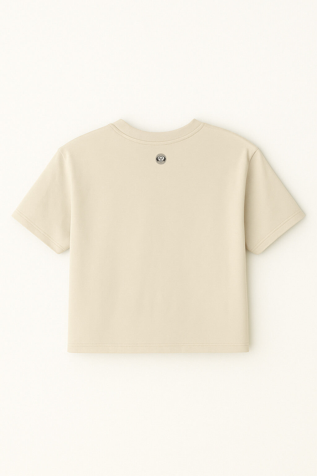 The Oversized Dog Mom Crop Top by Dogloverclothing.com is a relaxed fit beige crop top, shown from the back with a small round emblem at the neckline—ideal for embracing a casual Dog Mom Lifestyle.