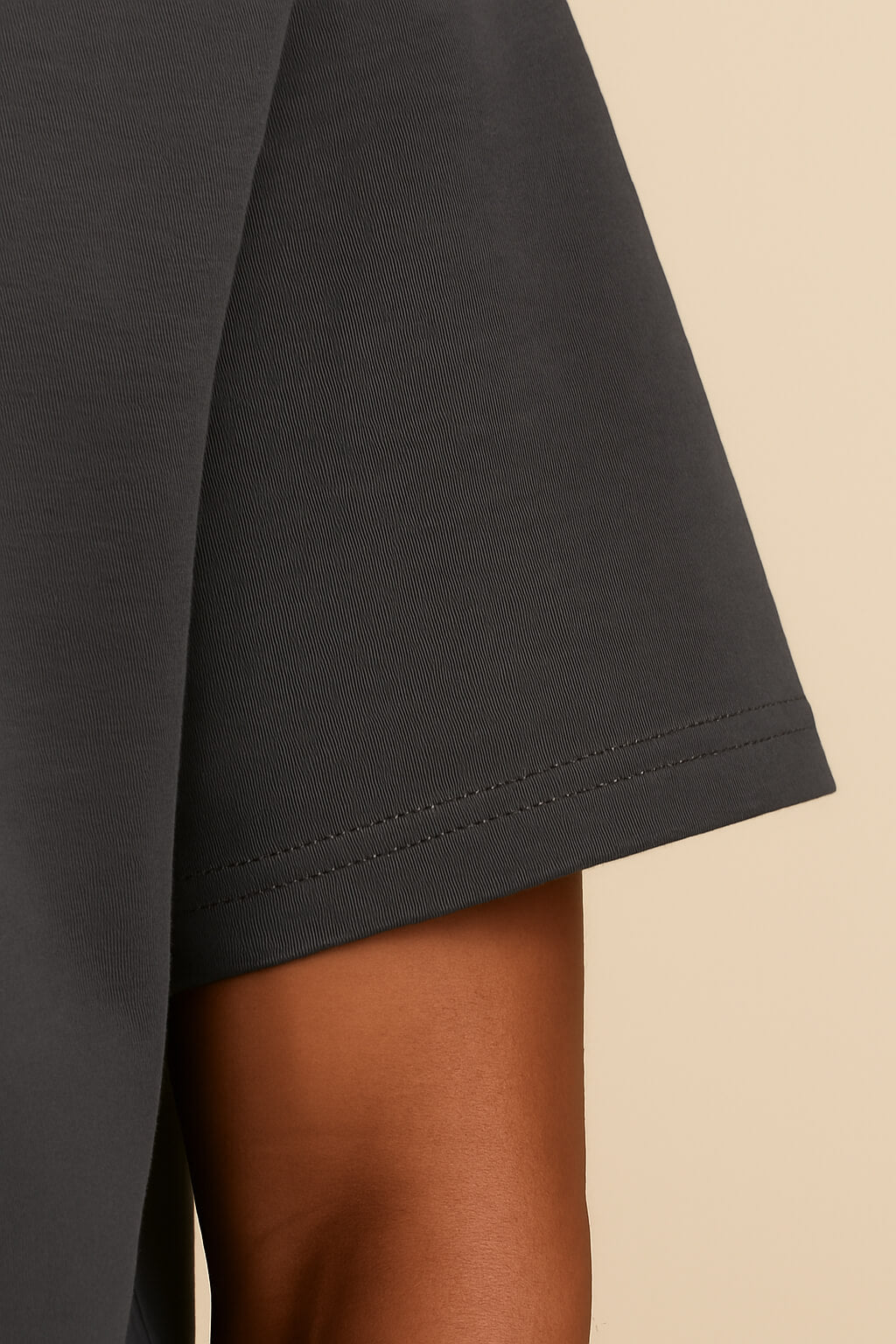 Close-up of a persons arm in an oversized Dog Dad T-shirt by Dogloverclothing.com, made from durable cotton. The dark gray tee features a relaxed fit and detailed sleeve stitching, set against a plain light beige background.
