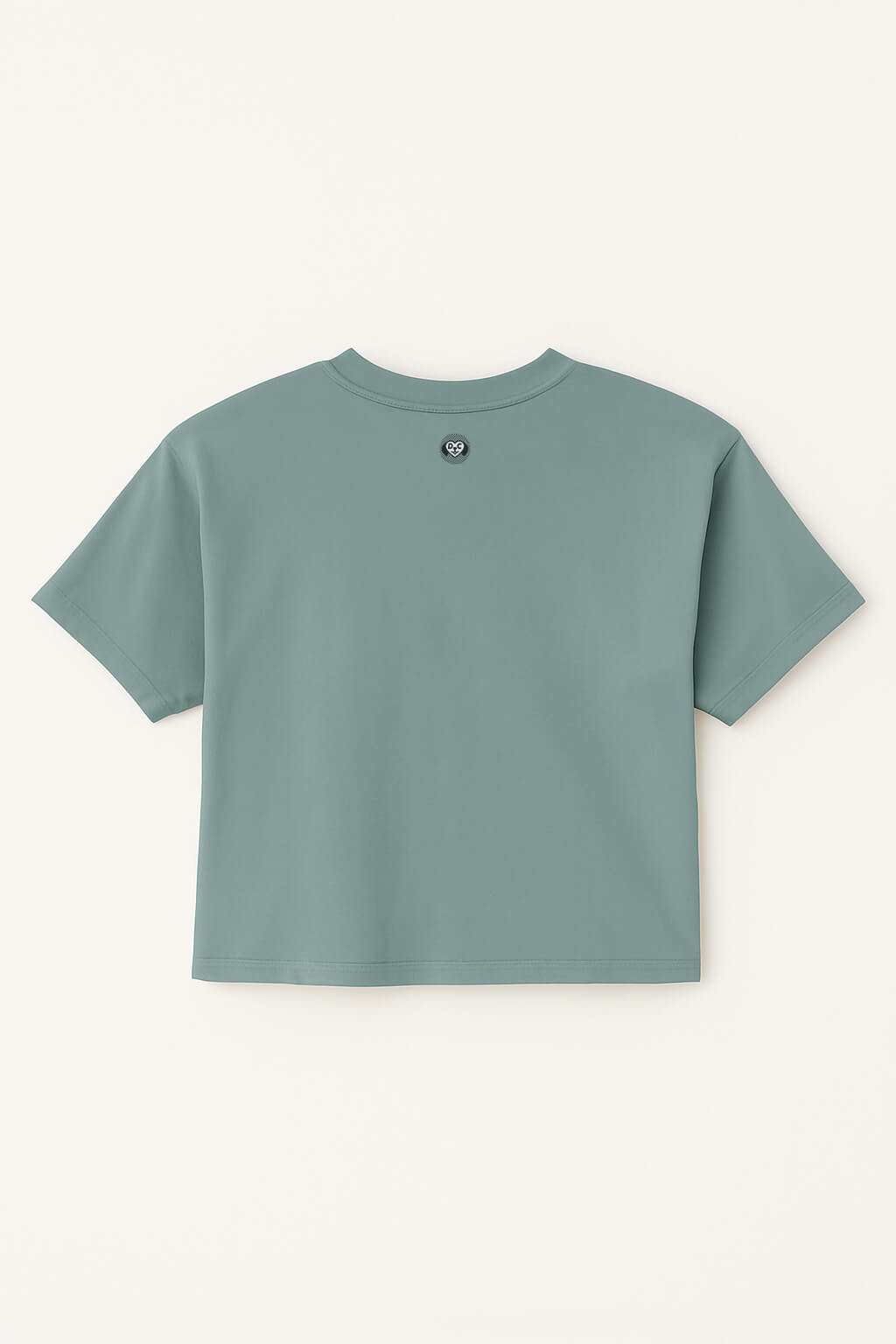 An Oversized Dog Mom Crop Top by Dogloverclothing.com is shown laid flat, back side up, in teal with a small circular logo near the neckline on a light cream background.