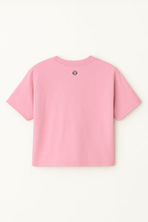 The Oversized Dog Mom Crop Top by Dogloverclothing.com is a plain pink combed cotton crop top with a small circular logo near the back neckline, perfect for embracing a relaxed, comfortable style.