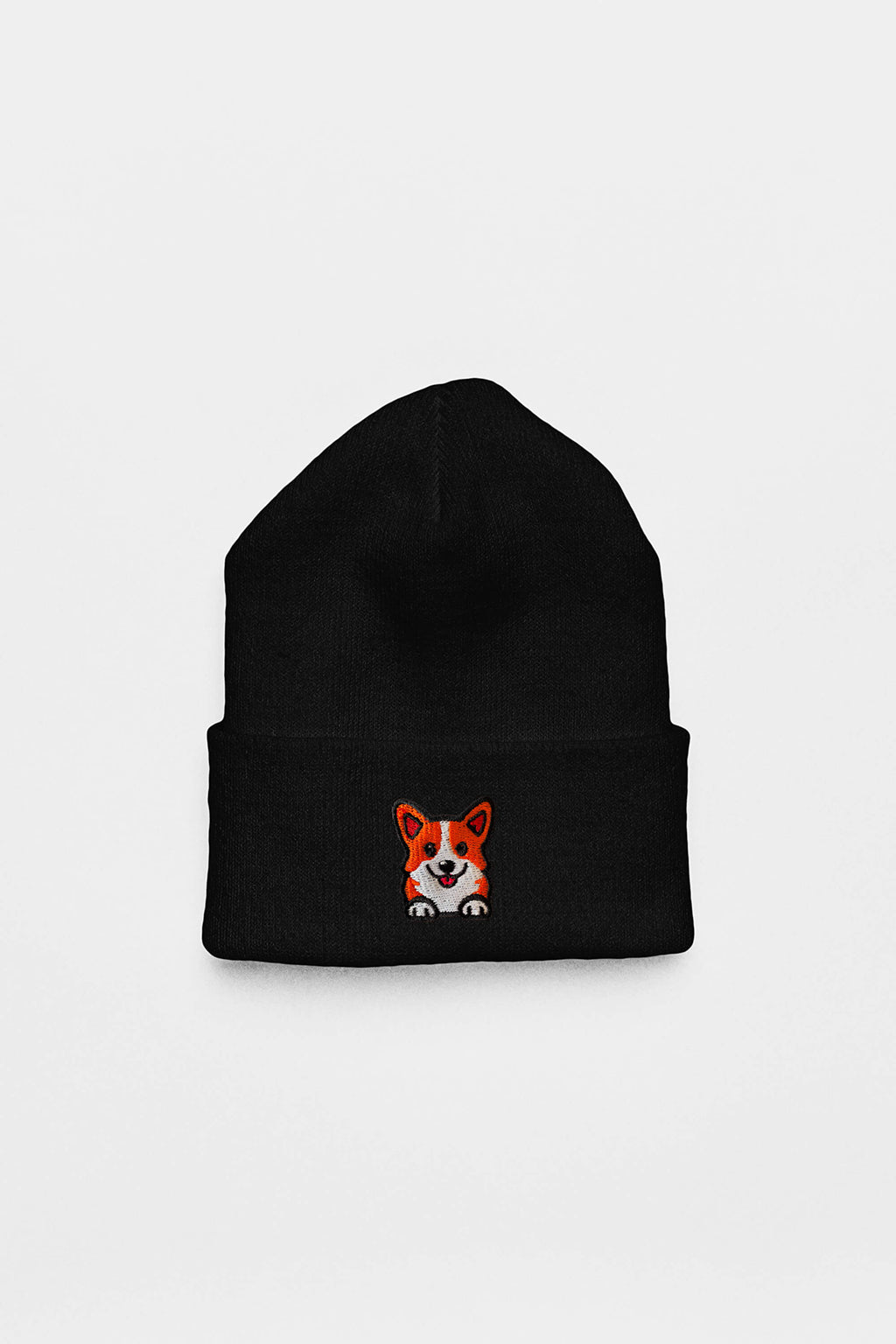 The Cozy Corgi Patch Beanie by Dogloverclothing.com is a black knit hat with a small embroidered smiling orange and white corgi face on the front fold, perfect for dog lovers. Shown against a plain white background.