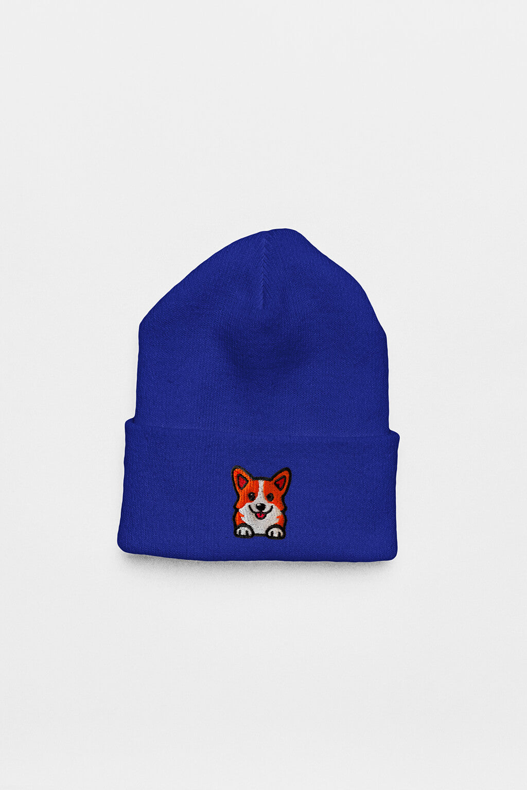 The Cozy Corgi Patch Beanie from Dogloverclothing.com is a royal blue beanie with a folded brim and an embroidered smiling corgi face—an adorable accessory for any dog lover.